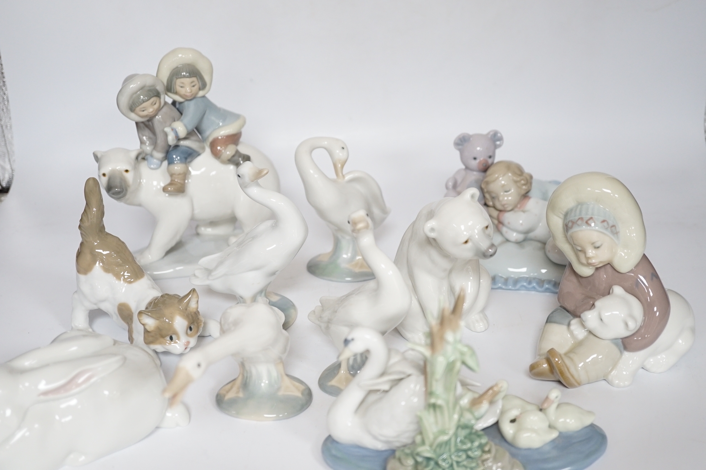 Eleven Lladro figure groups, including a collection of ducks, two Eskimo figure groups, a sleeping child with teddy on a cushion etc, none boxed